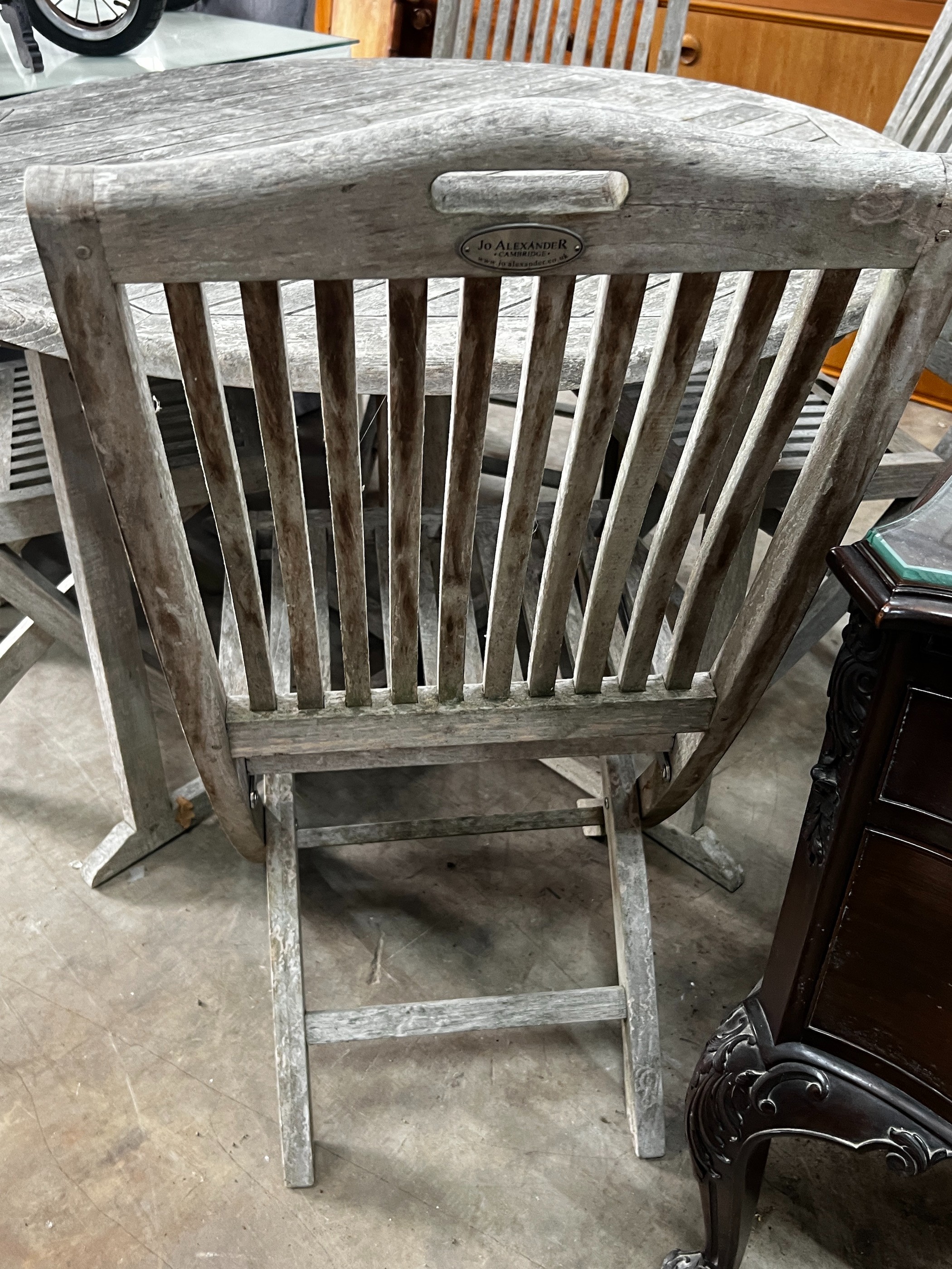 A Jo Alexander circular weathered teak folding garden table, diameter 120cm, height 75cm and four chairs *Please note the sale commences at 9am.